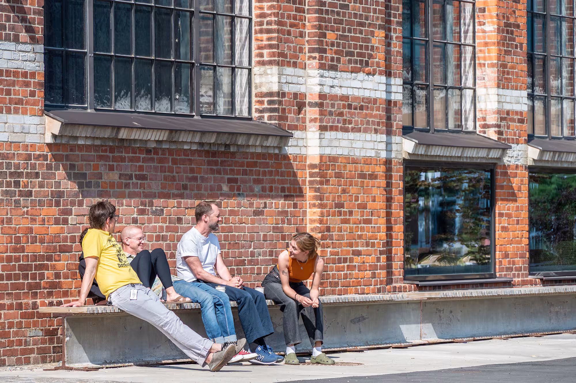 4 personer som sitter på en bänk och njuter av solen