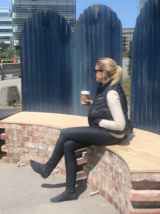 Kvinna sitter på bänk med kaffekopp