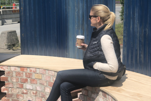 Kvinna sitter på bänk med kaffekopp